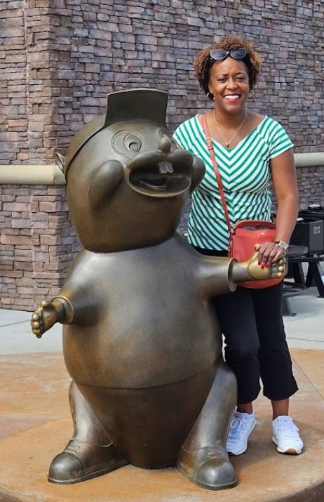 female solo traveler standing with a Buc-ee the Beaver statue at its gas-convenience store location during a road trip stop