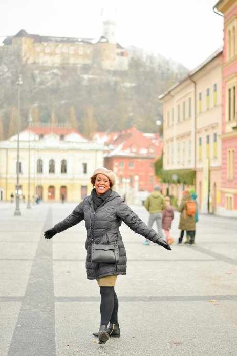 female solo traveler smiling with arms outstretched at her sides while standing in Congress Square in Ljubljana