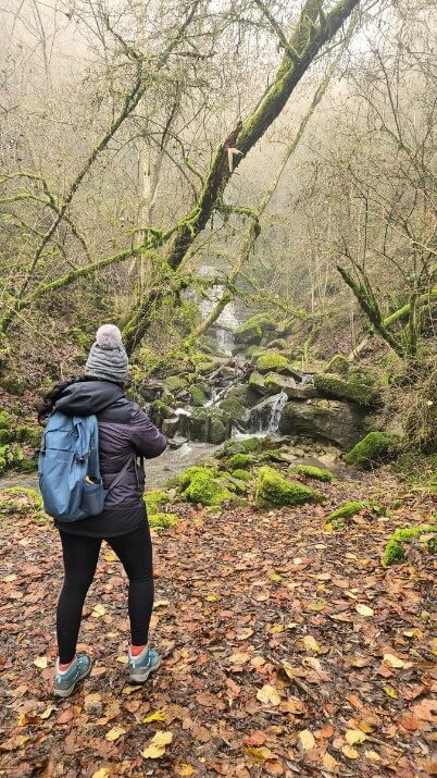 woman taking photo of a creek on a hike