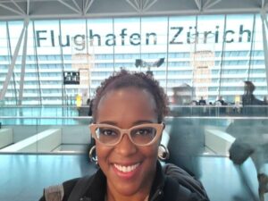 Headshot of smiling woman with Zurich Aiport sign behind her